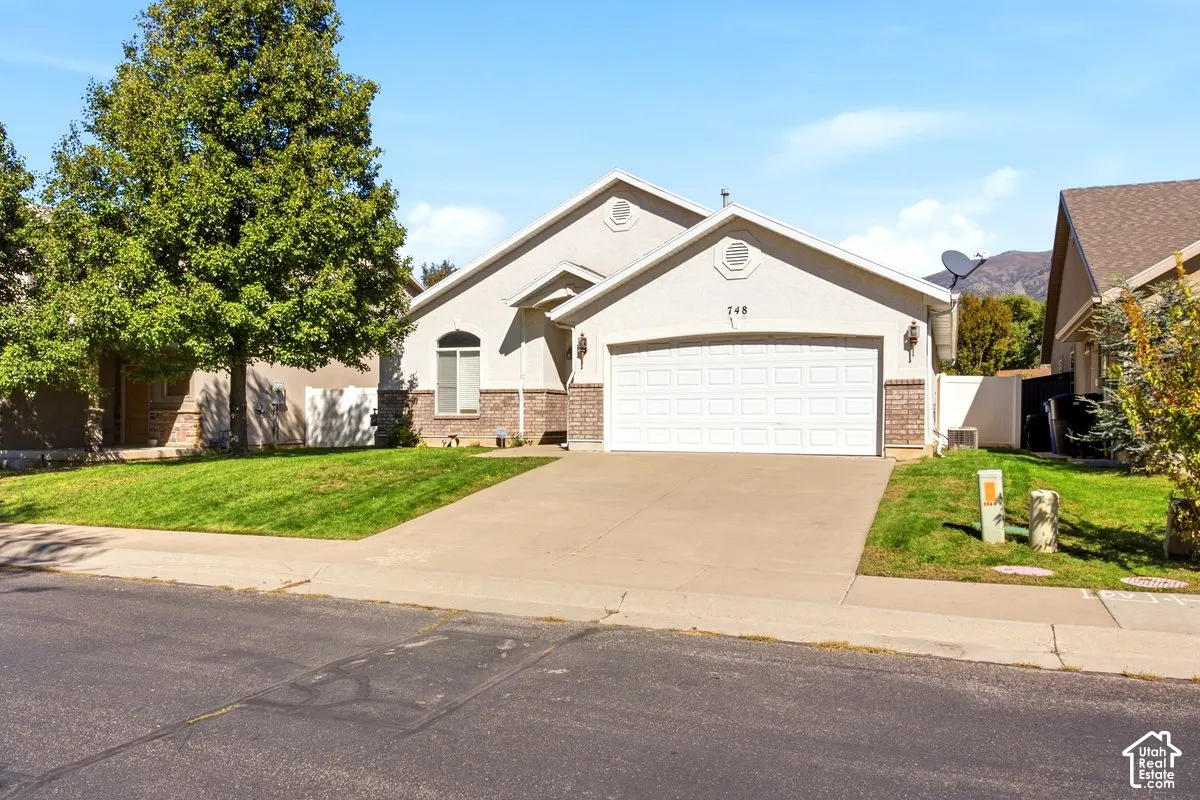 Stucco exterior featuring brick wainscoting, an arched window, and an attached two-car garage