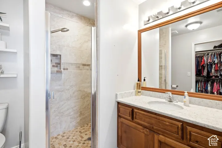 Glass-enclosed shower with stone tile surround and mosaic accent