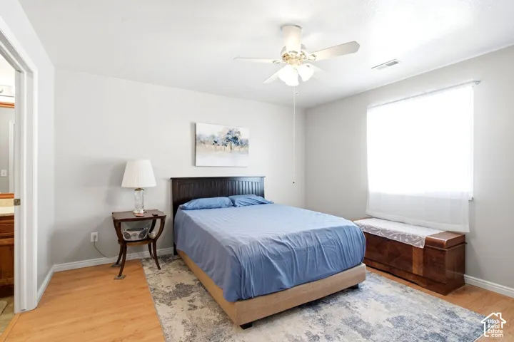 Bright secondary bedroom featuring hardwood flooring, a ceiling fan with integrated lighting, large window with natural light, and generous closet space