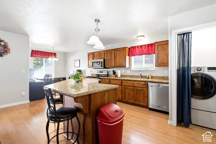 Kitchen featuring wood-finish flooring, wood cabinetry, granite countertops, and stainless steel appliances
