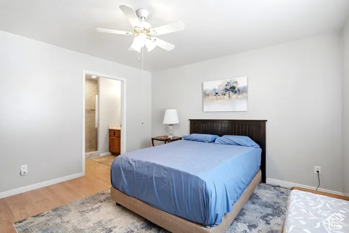 Recessed lighting and a ceiling fan fixture illuminate a room featuring wood-finish flooring