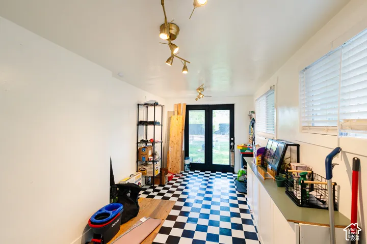 Black and white checkerboard flooring, dual French doors, track lighting, and multiple windows with blinds