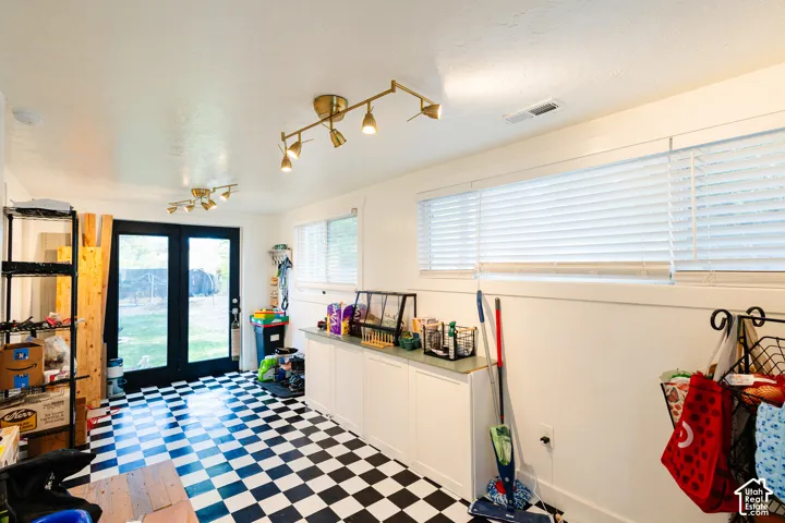 Checkerboard flooring, dual French doors, built-in cabinetry, track lighting, and horizontal blinds