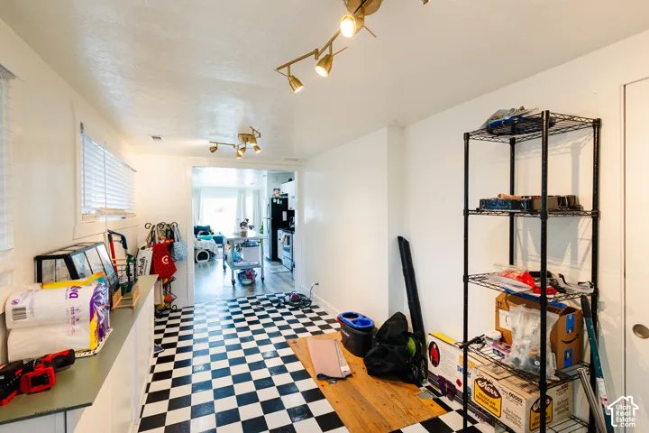 Black and white checkered flooring with track lighting and a pass-through opening to an additional room