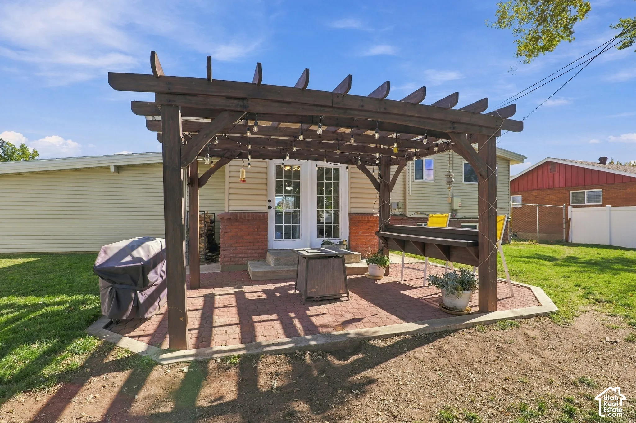 Pergola-covered patio featuring brick pavers, double glass panel doors, and a wood lattice structure