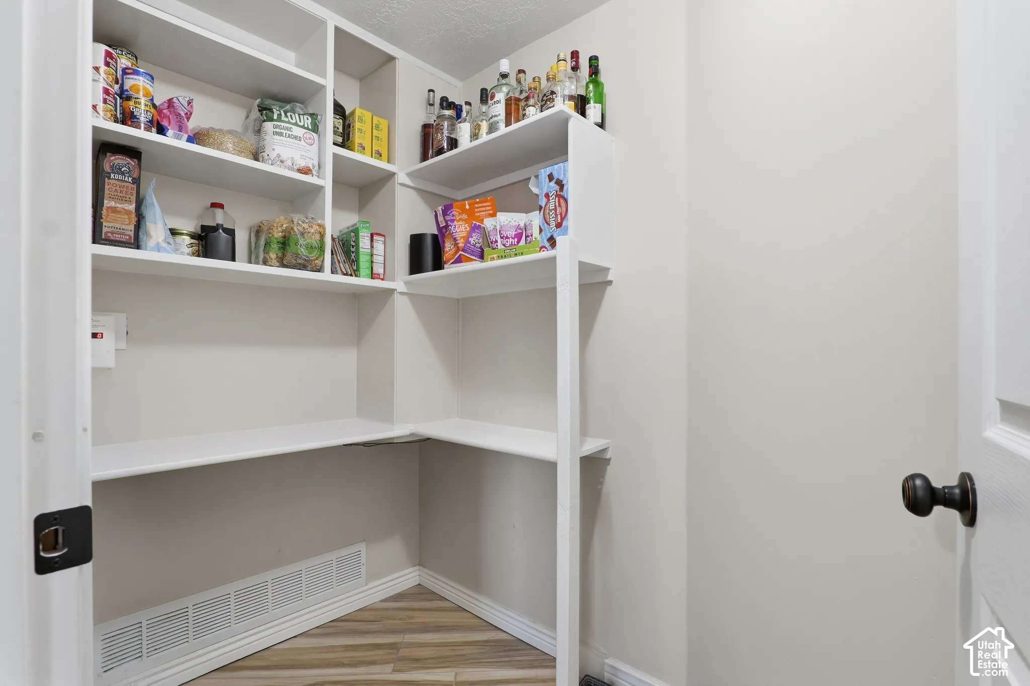 Built-in shelving with multiple levels, wood-finish flooring, and a solid core door with bronze hardware
