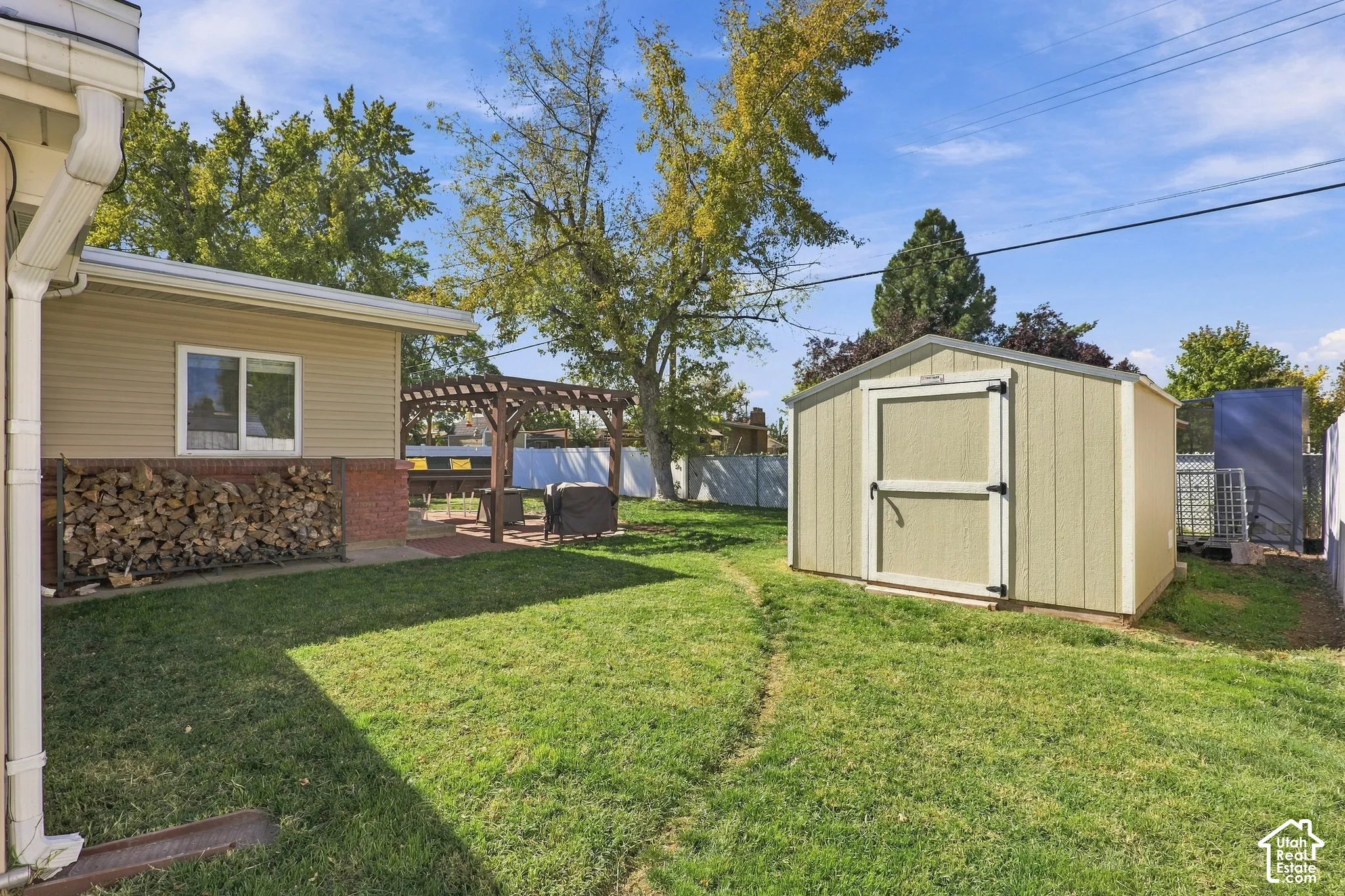 Expansive backyard featuring a storage shed, a wood pergola, and a brick patio
