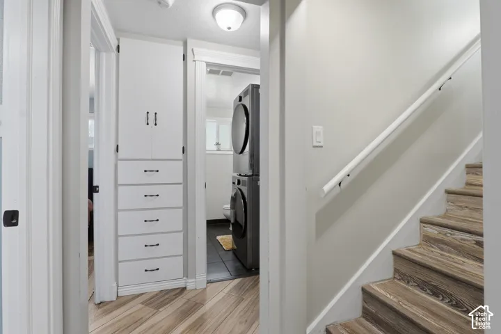 Built-in white cabinetry with drawers, wood-finish flooring, and a white staircase with a handrail