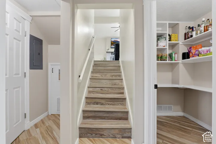 Wood-finish flooring throughout, a staircase with a white handrail, built-in shelving, and white interior doors