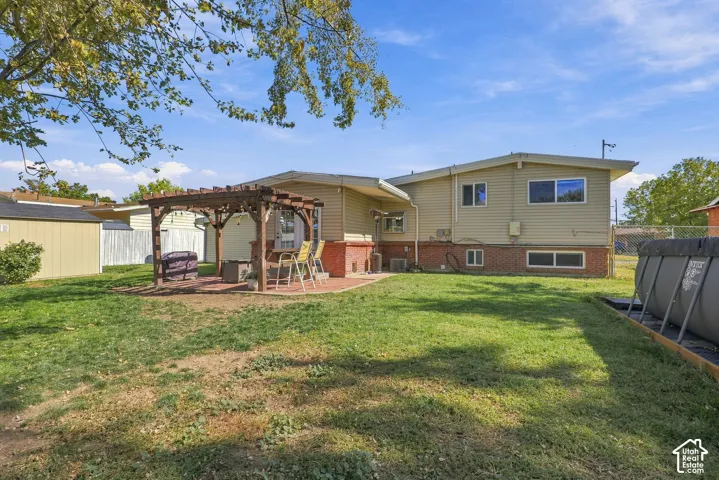 Expansive backyard with a wooden pergola, brick paver patio, and detached storage shed