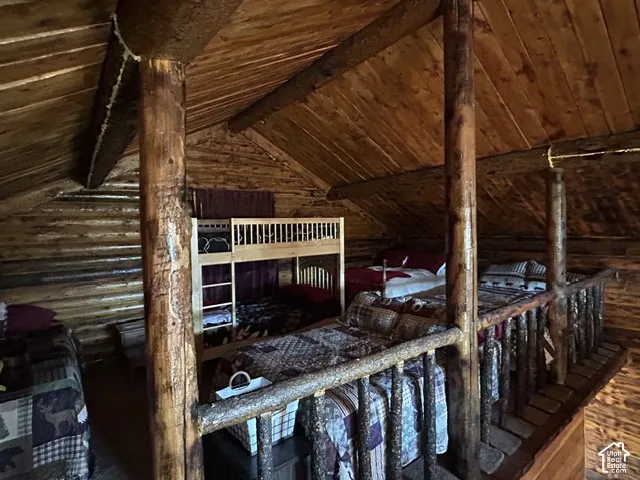 Vaulted wood plank ceiling, exposed wood beams, log wall construction, and a wood railing