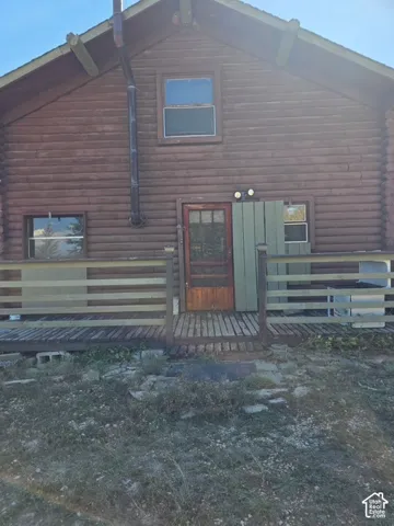 Log cabin exterior with an A-frame roofline, featuring a covered wooden porch and multiple windows