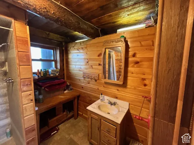 Pine paneling throughout, wood-finish flooring, single window, vanity with integrated sink, and built-in shelving