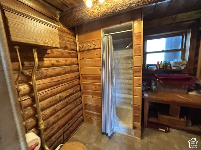 Log walls, wood-finish flooring, built-in shelving, and a window provide natural light