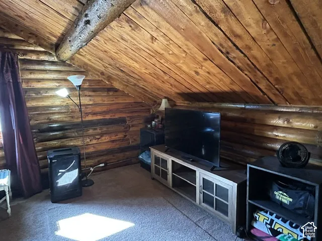 Exposed log walls, sloped wood-paneled ceiling, and a large window opening