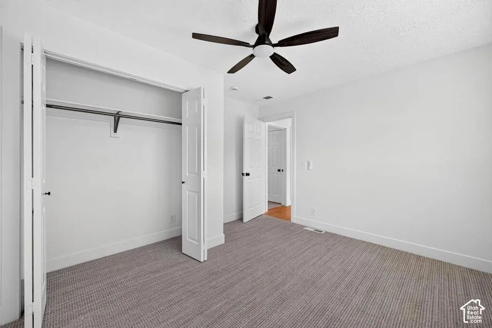 Carpeted room featuring a ceiling fan, bifold closet doors, and solid interior doors