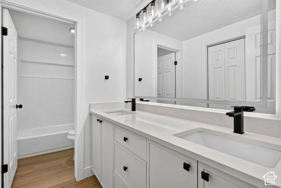Dual vanity with white cabinetry and integrated sinks, matte black fixtures, full-width mirror, and overhead linear lighting