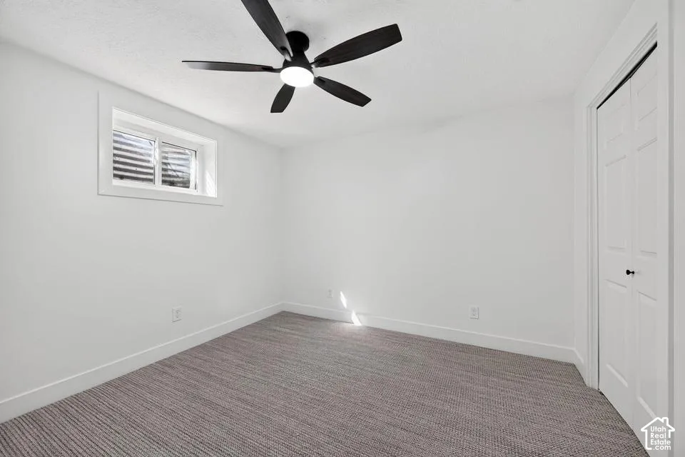 Recessed window, white walls, textured carpeting, bi-fold closet, and ceiling fan with integrated lighting