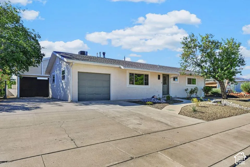 Stucco exterior with an attached garage, a separate carport, a concrete driveway, and low-maintenance landscaping