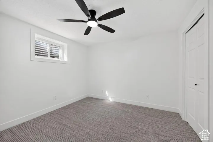 Recessed window, white walls, textured carpeting, bi-fold closet, and ceiling fan with integrated lighting