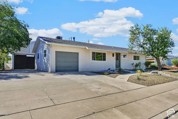 Stucco exterior with an attached garage, a separate carport, a concrete driveway, and low-maintenance landscaping
