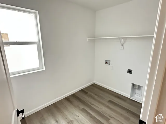 Laundry room with wood-finish flooring, white walls, and a single window