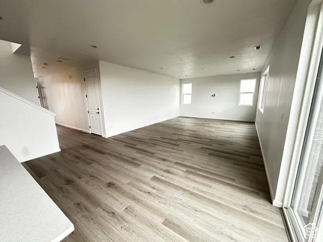 Expansive room featuring wood-finish flooring, recessed lighting, and multiple windows