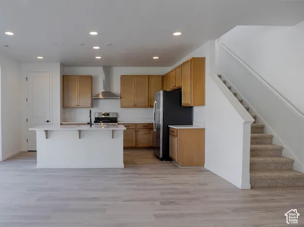 Kitchen featuring an island with white countertop, wood-finish cabinetry, stainless steel appliances, and a range hood