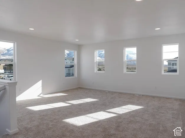 Recessed lighting, white walls, multiple windows, neutral carpet, and white trim