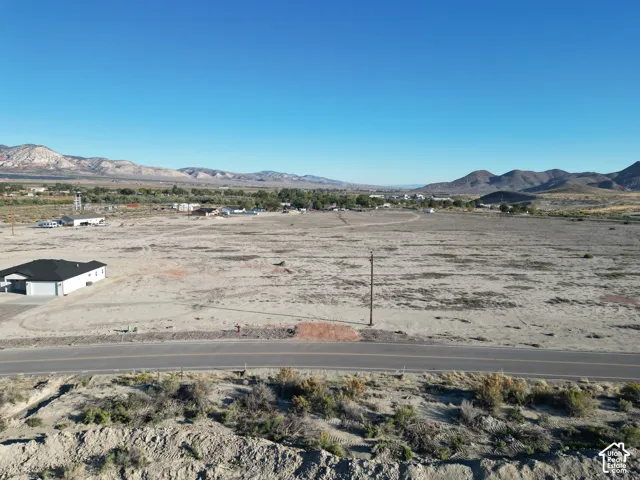 Expansive undeveloped land featuring a paved road and distant mountain scenery