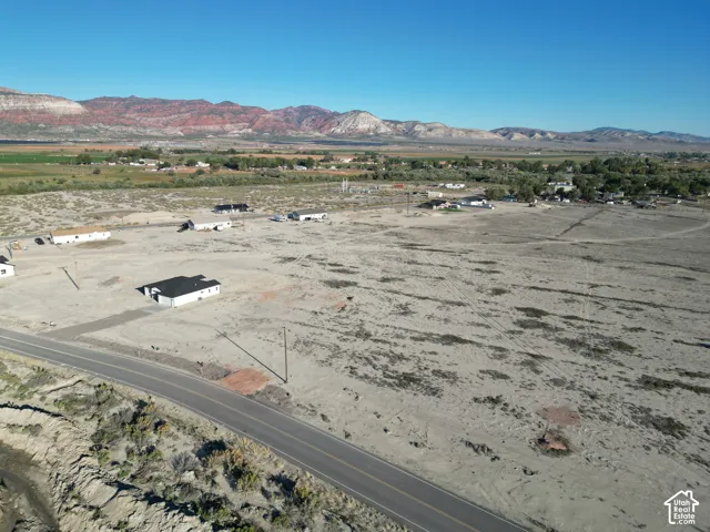 Expansive undeveloped land featuring a paved roadway, utility infrastructure, and distant mountain scenery