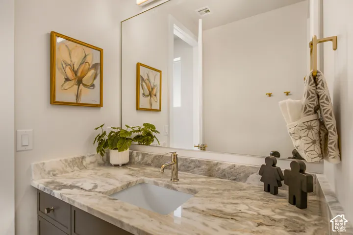 Vanity with a polished stone countertop, undermount sink, and brushed nickel faucet