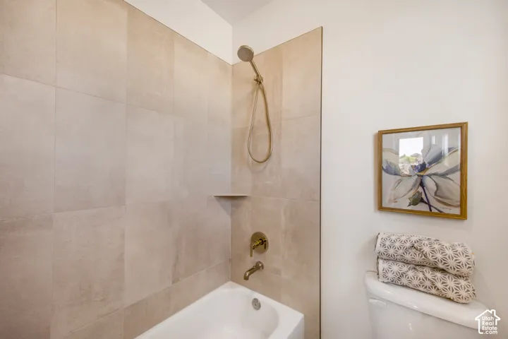 Bathtub with a tiled surround, integrated shower niche, and brass-finish fixtures