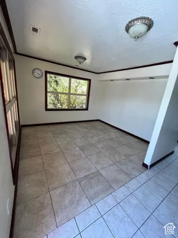 Room with large window, two ceiling-mounted light fixtures, tile flooring, and dark trim details