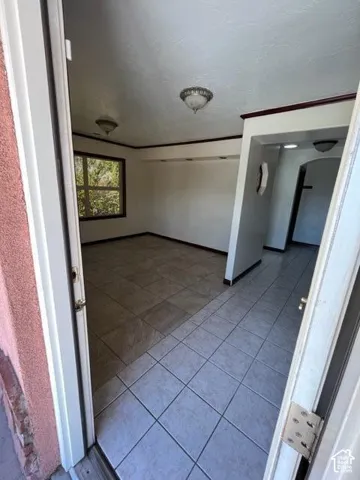 Neutral-toned tile flooring throughout, featuring a window with dark trim, recessed display shelving, and decorative ceiling-mounted light fixtures