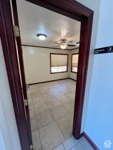 Tile flooring, ceiling fan, and multiple windows with blinds