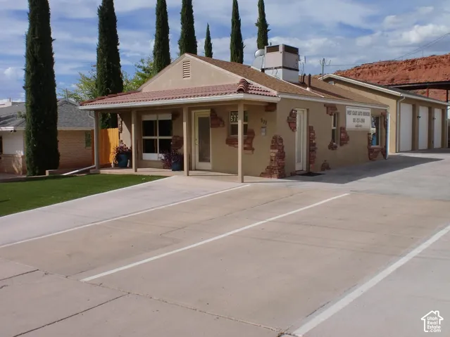 Stucco exterior with decorative brick accents, covered entry, front-facing windows, and a paved parking area