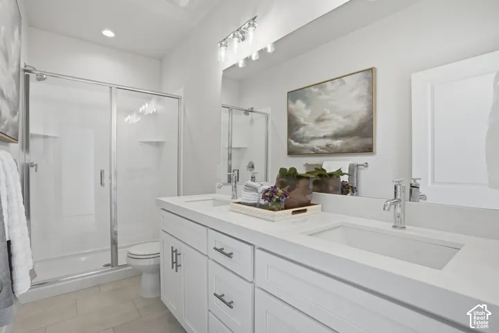 Dual undermount sinks with chrome fixtures, white shaker-style cabinetry, and light-toned tile flooring