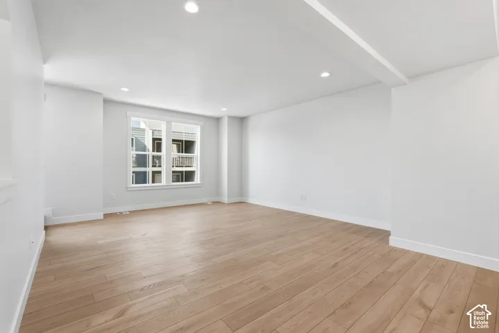 Recessed lighting, wood-finish flooring, white walls, and a large window with white trim
