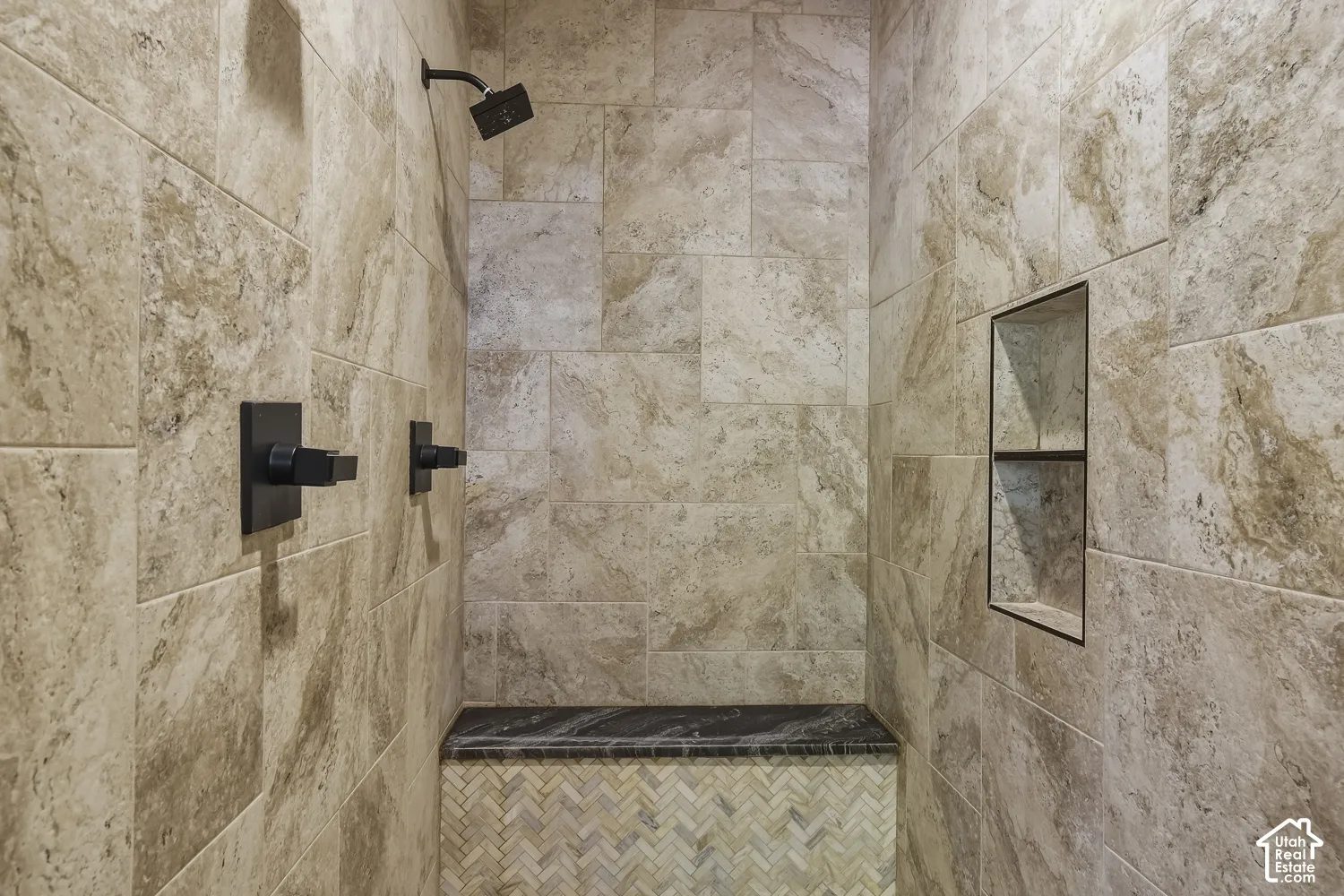 Walk in shower in primary ensuite with bench, built in storage, and dual shower heads