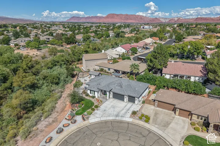 Aerial view showing creek running next to the home and red mountains in the distance