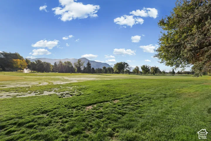 Expansive green space featuring mature trees and distant mountain ranges