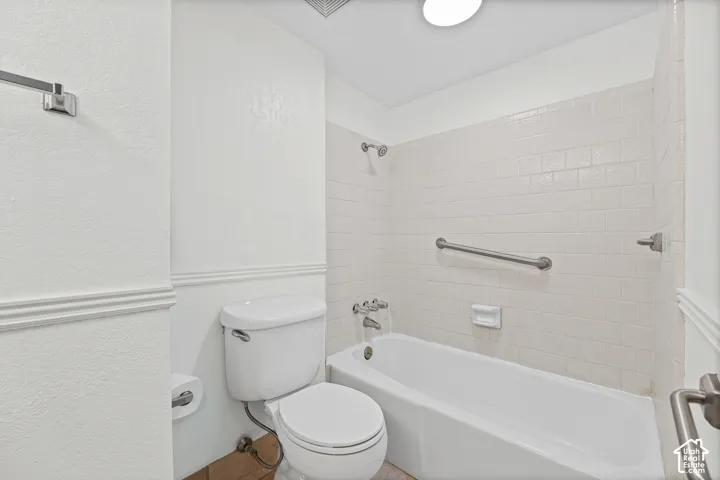 Tub and shower combination with subway tile surround, polished chrome fixtures, and a grab bar