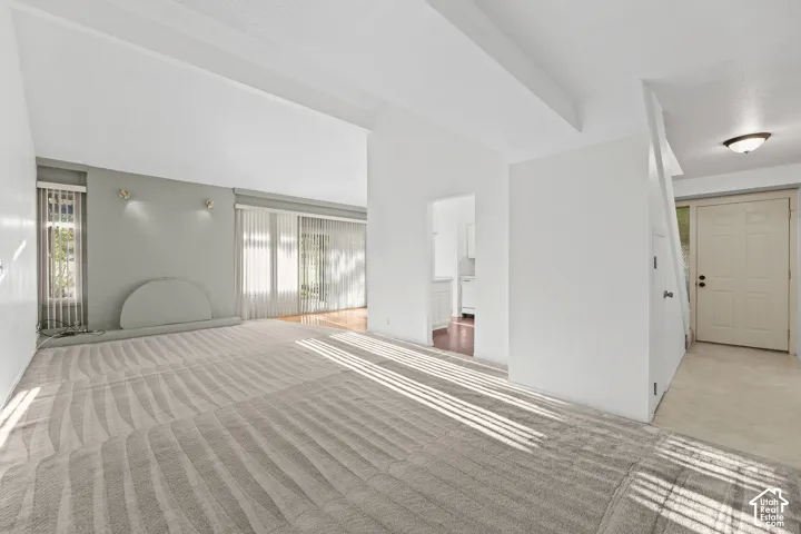 Spacious room featuring patterned carpeting, recessed lighting, and large windows with vertical blinds