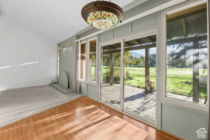 Expansive glass sliding doors and windows, stained glass ceiling fixture, wood-finish flooring, vaulted ceiling, and built-in wall sconces