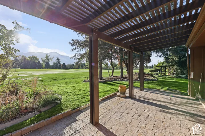 Patio featuring a slatted pergola, stamped concrete, and a planted border