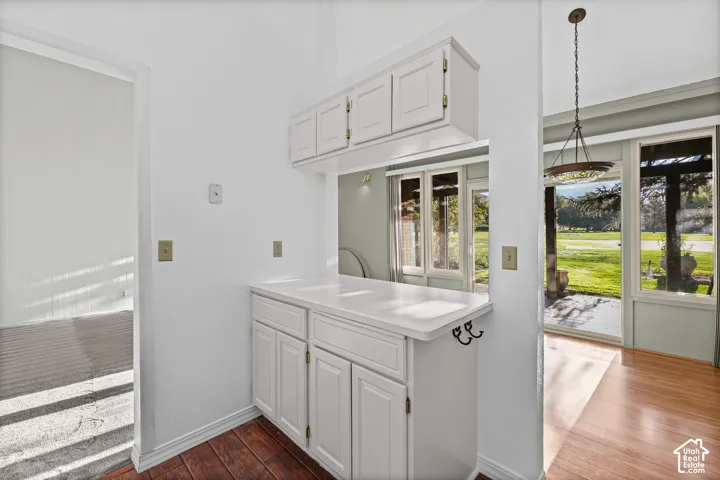 Built-in white cabinetry with a pass-through window, white countertop, and wood-finish flooring