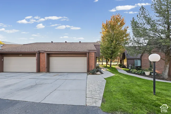 Attached garages, brick facade accents, manicured lawn, established trees, and paved walkways