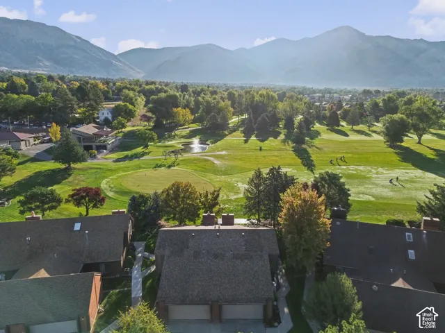 Mountain backdrop overlooking a golf course with mature trees, expansive green spaces, and a pond with a fountain feature