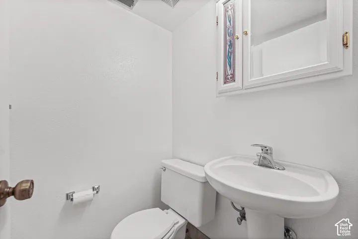 White pedestal sink with chrome faucet, toilet, and mirrored medicine cabinet